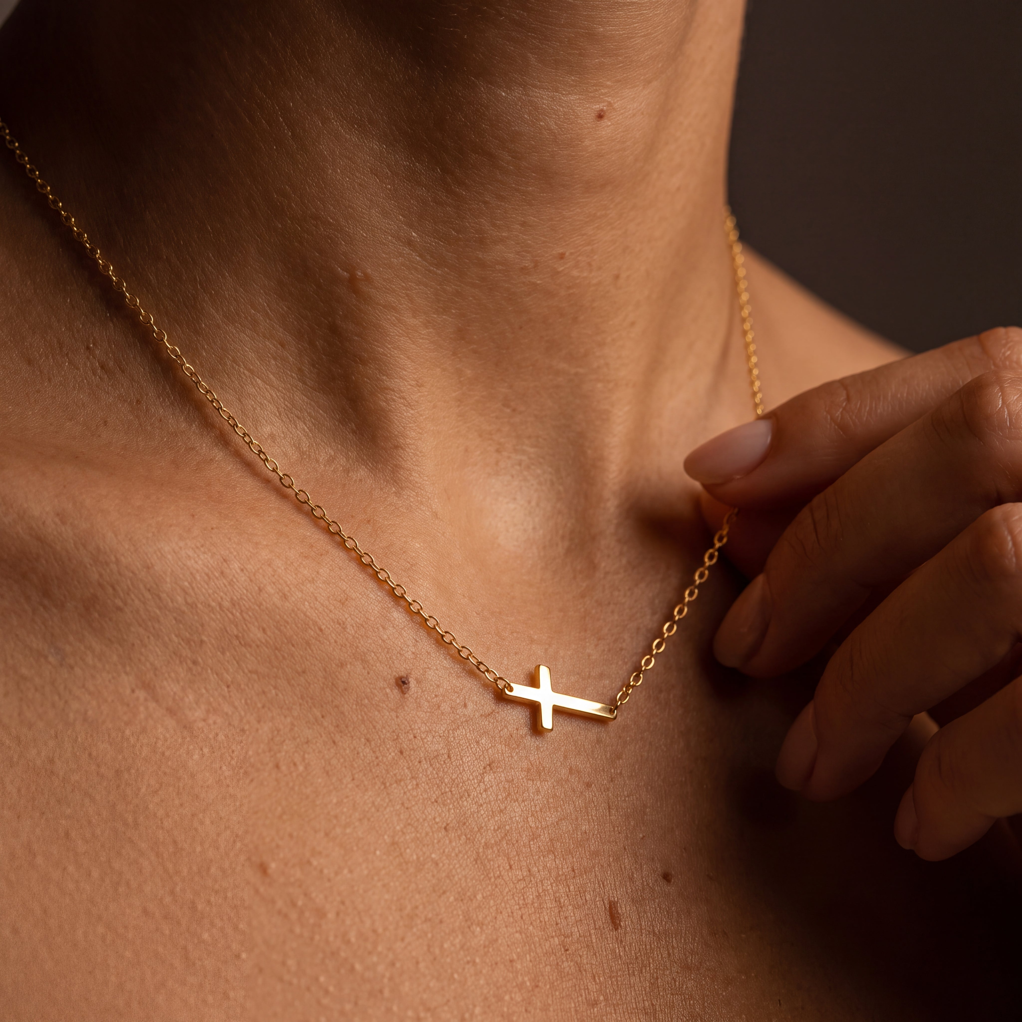 Dainty gold sideways cross necklace on a fine stainless steel chain