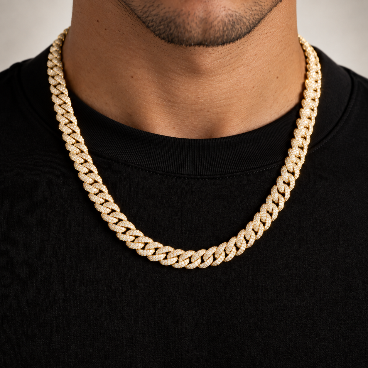Gold-tone iced Miami Cuban link chain worn over a black t-shirt, prong-set stones