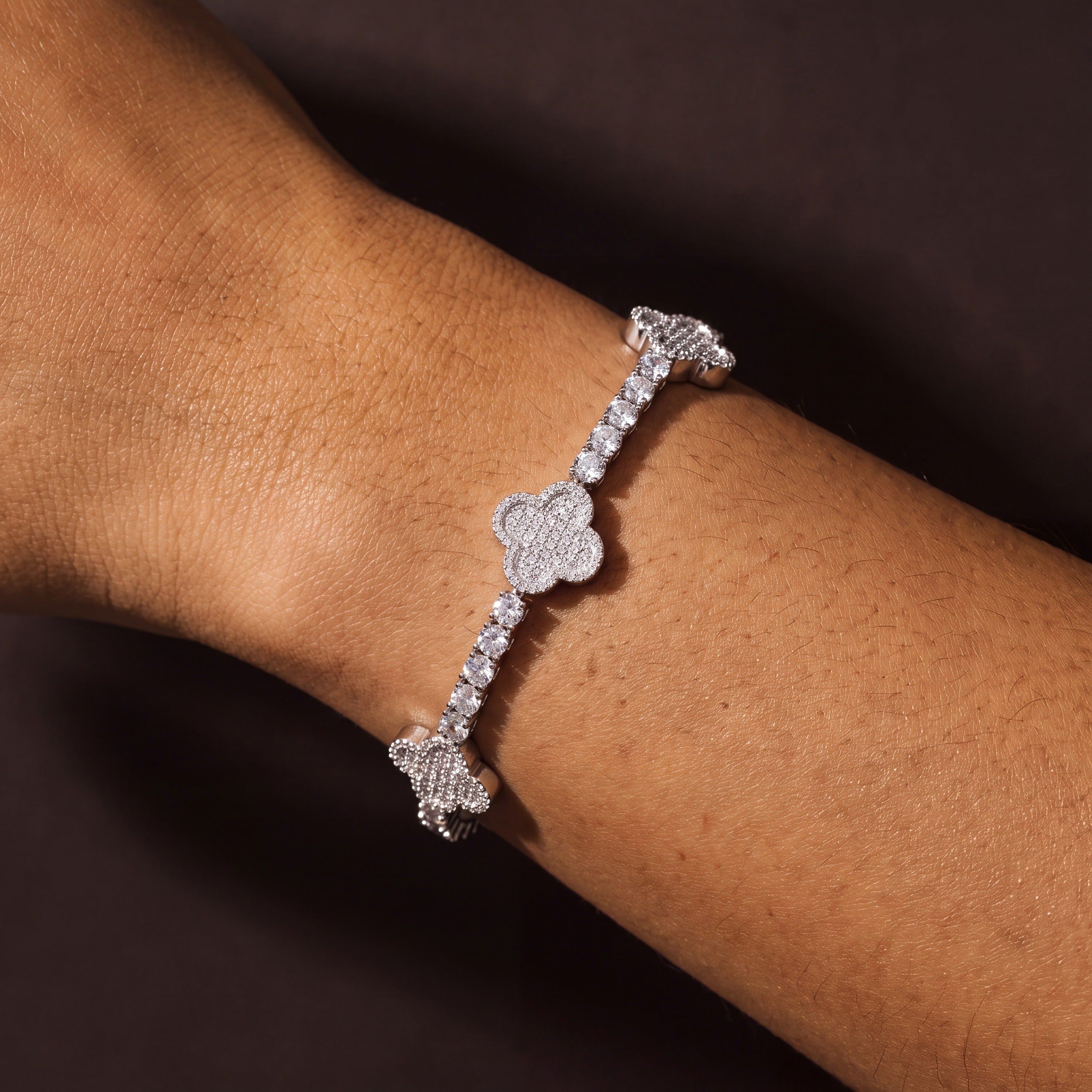 Silver-tone four-leaf clover tennis bracelet worn on a wrist