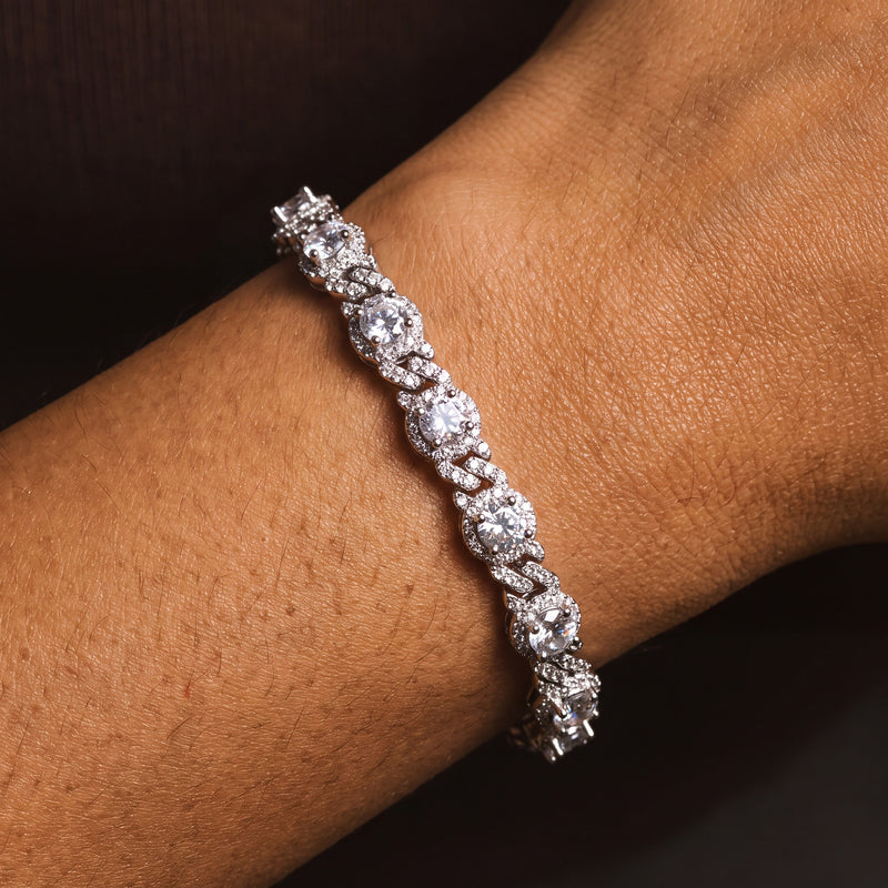 Silver-tone halo station Cuban link bracelet worn on a wrist