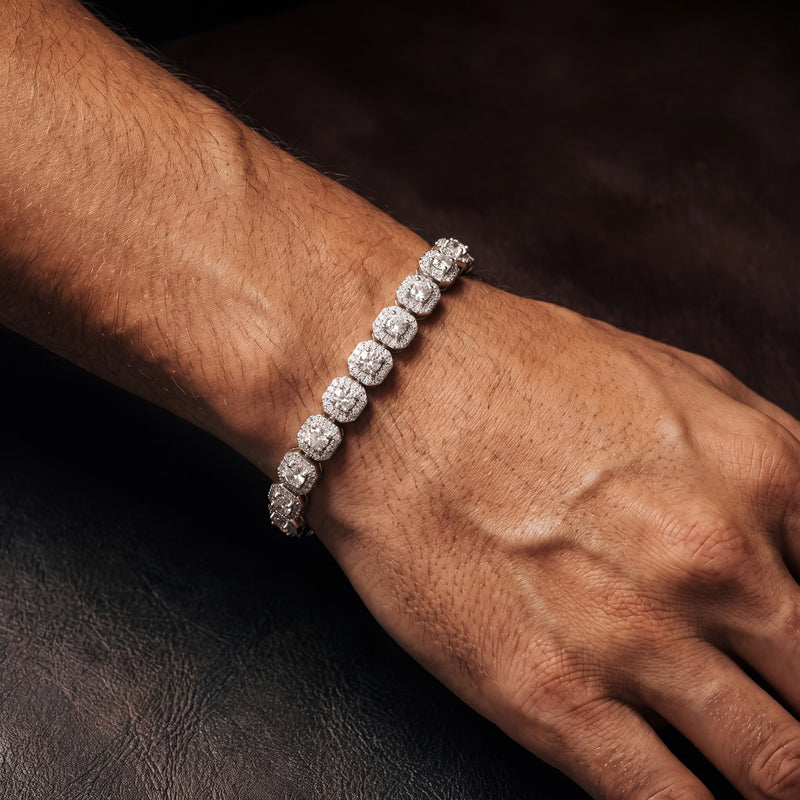 Iced cluster tennis bracelet worn on a wrist, halo-set cubic zirconia stations in silver tone